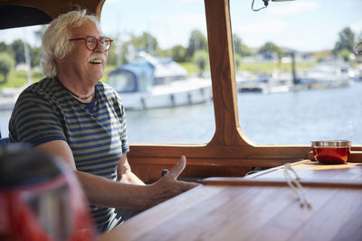 Happy senior man wearing eyeglasses sailing boat