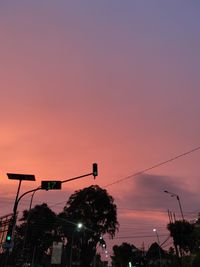 Low angle view of illuminated street lights against sky at sunset