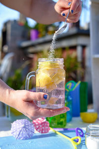 Woman preparing a cocktail, pour the sugar into the glass with pieces