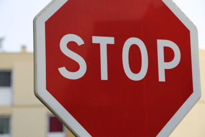 Close-up of road sign against red wall