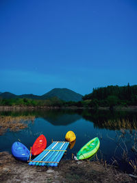 Multi colored boats moored in lake against blue sky