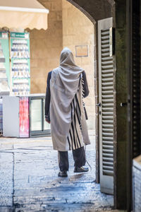 Rear view of woman walking on footpath by street