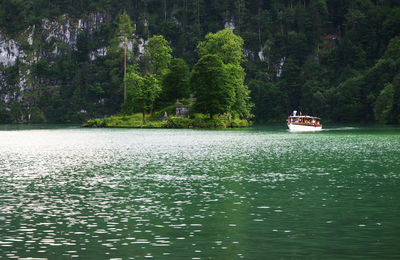 Sailboat sailing on sea by trees