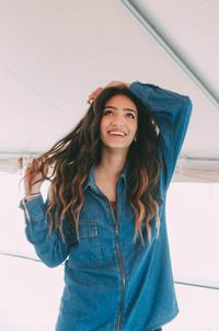 Portrait of smiling young woman standing against wall