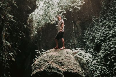 Full length of man standing on rock in forest