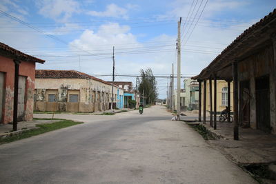 Empty road amidst buildings against sky