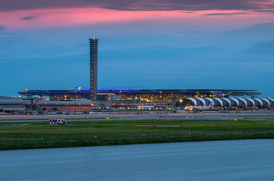 Scenic view of illuminated city against sky at sunset