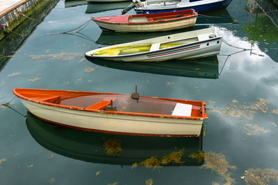 Old boats filled with water are moored with ropes in the port. sea water with seaweed and raindrops