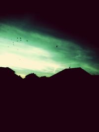 Silhouette of birds flying against sky