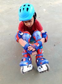 High angle view of sad boy with inline skates sitting at playground