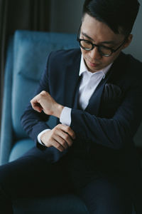 Man wearing suit while sitting on chair at home