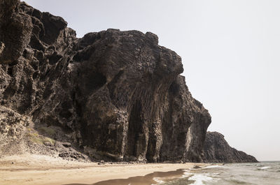 Rock formation on beach against clear sky