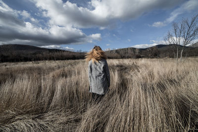 Rear view of woman standing on field against sky