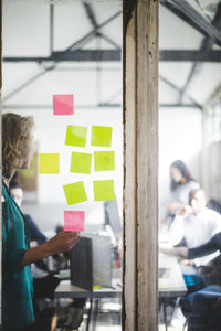 Businesswoman giving presentation to it professionals seen through glass wall in creative office