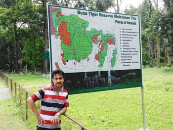 Portrait of man standing by map in forest