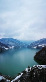 Scenic view of lake by snowcapped mountains against sky