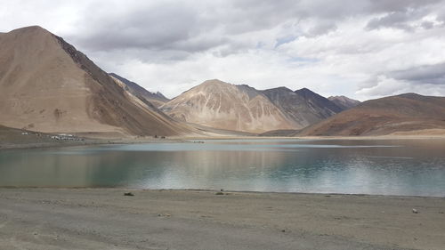 Scenic view of lake by mountains against sky