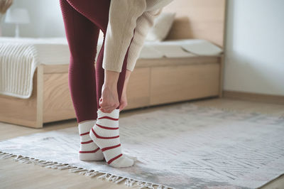 Low section of woman standing on bed at home