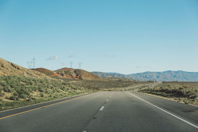 Road by mountains against clear sky