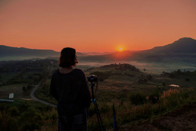 Rear view of  woman photographing at sunset