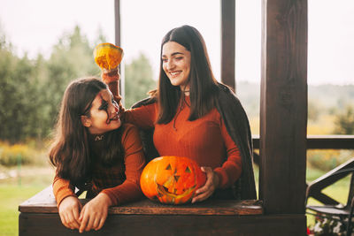 Two sisters celebrate halloween on the street near the house in costumes and make-up 