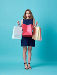 Portrait of woman standing against blue background