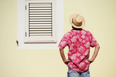 Rear view of woman standing against wall