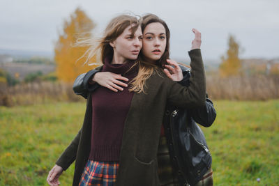 Portrait of young woman with friend standing on field