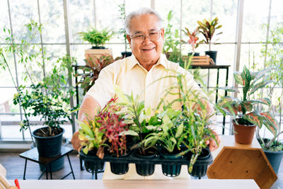 Portrait of smiling man standing by potted plants