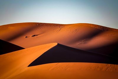 Low angle view of sand dunes against clear sky