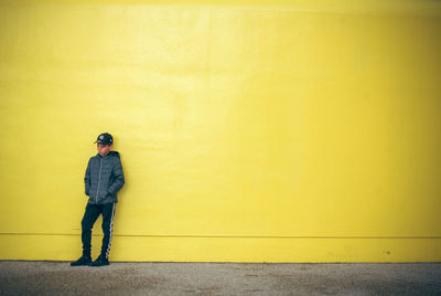 Full length of man standing against yellow wall