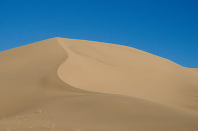 Scenic view of desert against clear blue sky