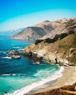 Scenic view of sea and mountains against clear blue sky