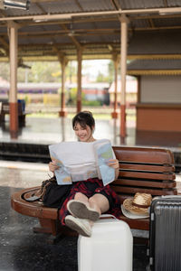 Portrait of young woman using mobile phone while sitting on table