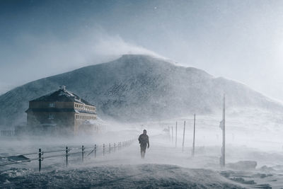 Rear view of person on snowcapped mountain against sky