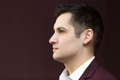 Portrait of young man looking away against black background