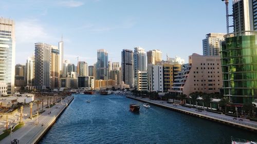 Canal amidst buildings in city against sky