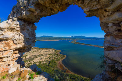 Rock formations by sea against clear blue sky