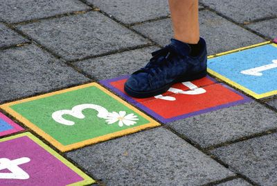 Low section of child playing hopscotch on footpath