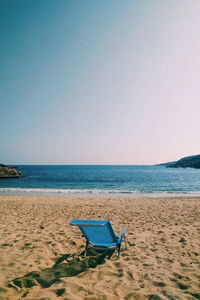 Deck chairs on beach against clear blue sky