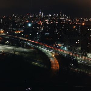 Light trails on road in city against sky at night