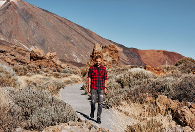 Rear view of man standing on mountain against sky