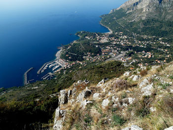 Scenic view of sea by mountain against sky