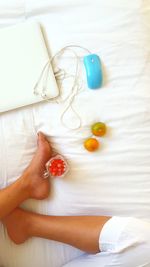 Low section of woman having food and drink by laptop on bed