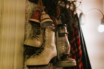 Retro old women's figure skates hang on a hanger on the wall with a vintage kerosene lamp
