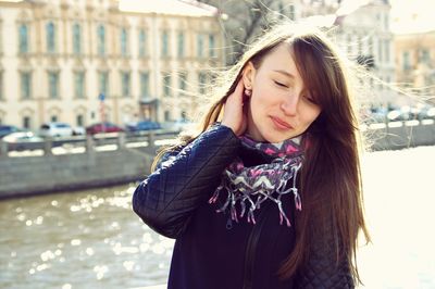 Smiling beautiful woman with hand in hair standing against anichkov bridge