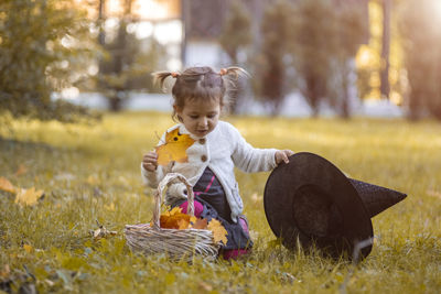 Halloween concept. cute little girl playing with witch hat in autumn park