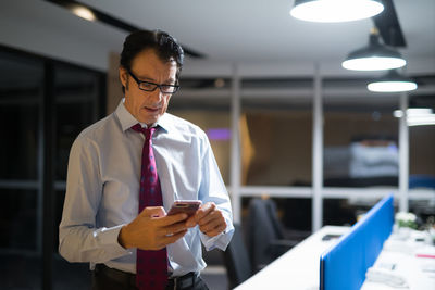 Businessman using mobile phone while standing at office