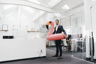 Businessman in office with inflatable flamingo