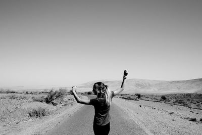 Young woman photographing on desert against clear sky